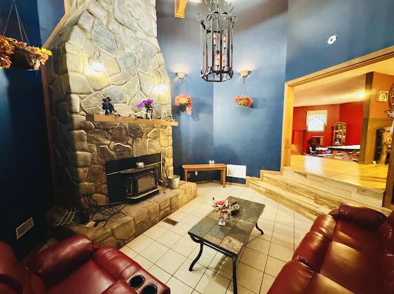 tiled living room with a high ceiling and a wood stove