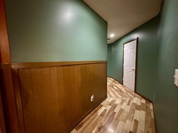 corridor featuring wooden walls and light hardwood / wood-style flooring