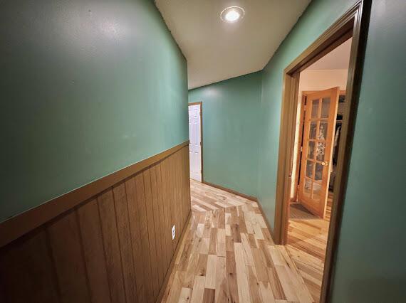 corridor featuring wood walls and light wood-type flooring