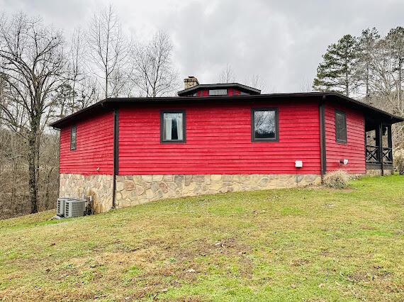 view of side of home featuring a lawn and central AC unit