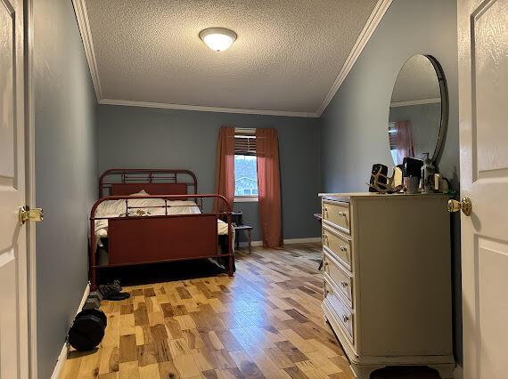 bedroom featuring crown molding, light wood-type flooring, and a textured ceiling