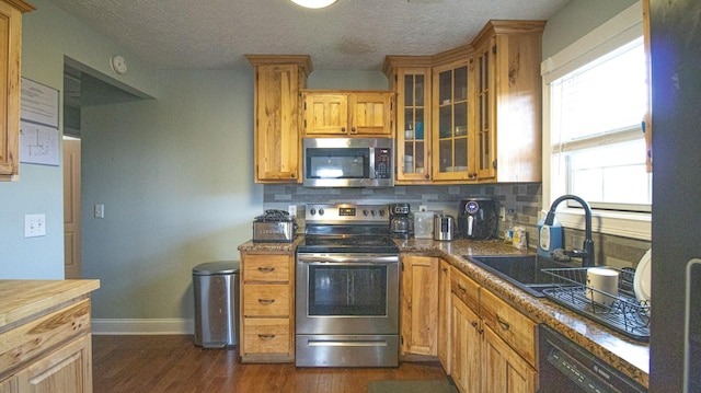 kitchen with appliances with stainless steel finishes, decorative backsplash, dark wood-type flooring, a textured ceiling, and sink