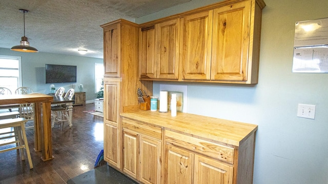 kitchen with a textured ceiling, dark hardwood / wood-style floors, wooden counters, and a healthy amount of sunlight