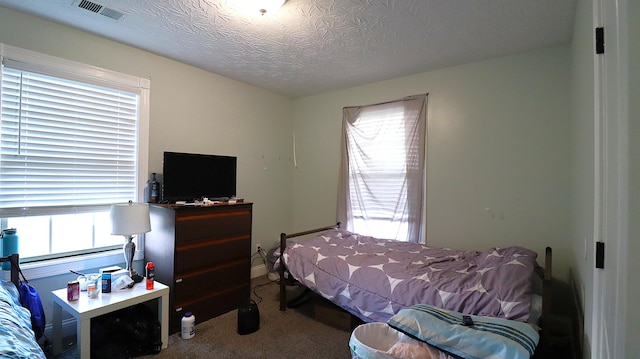 bedroom featuring a textured ceiling and light carpet