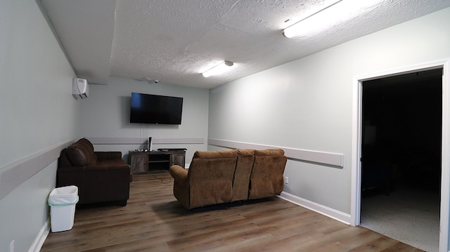 living room featuring a textured ceiling, a wall unit AC, and wood-type flooring