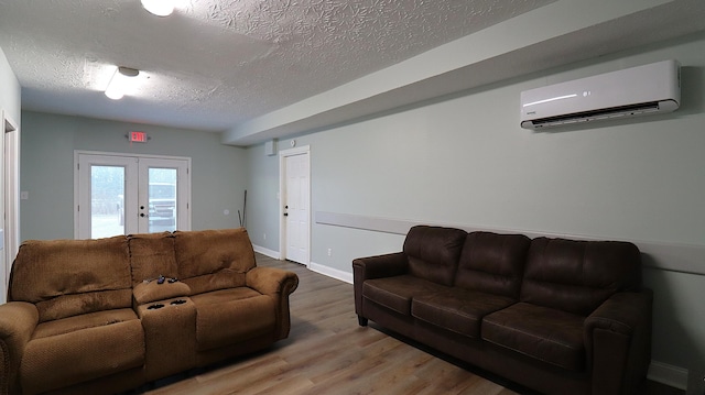 living room featuring an AC wall unit, french doors, a textured ceiling, and hardwood / wood-style floors