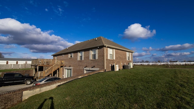 view of property exterior with a lawn, central air condition unit, and a deck