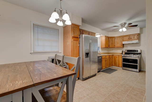 kitchen with kitchen peninsula, appliances with stainless steel finishes, ceiling fan with notable chandelier, sink, and decorative light fixtures