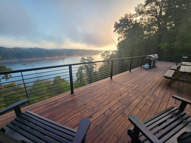 deck at dusk featuring a water view