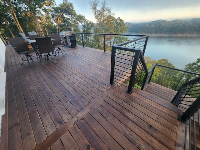 wooden deck featuring a water view and a grill