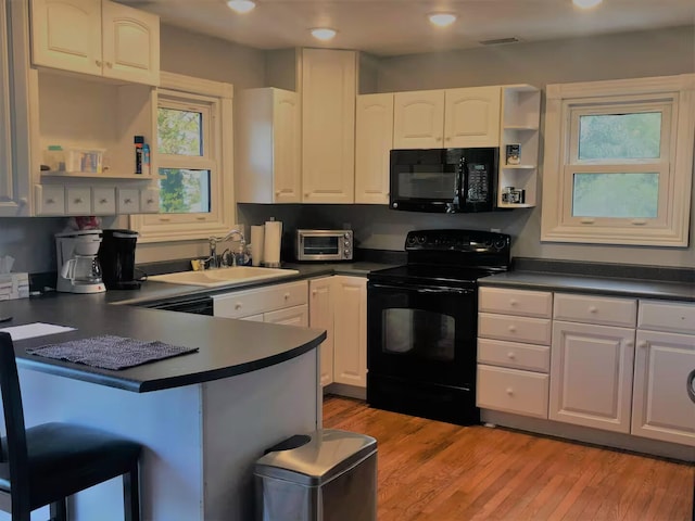 kitchen with white cabinets, sink, light hardwood / wood-style flooring, and black appliances