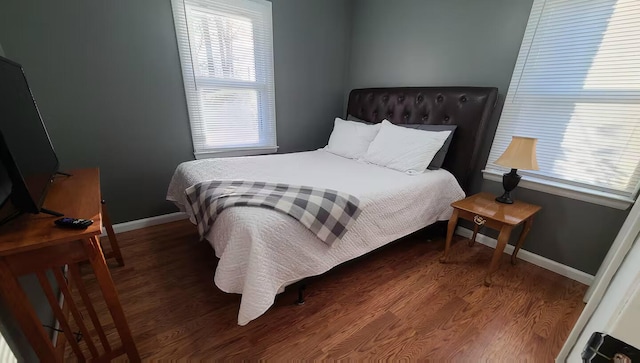 bedroom with dark hardwood / wood-style flooring and multiple windows