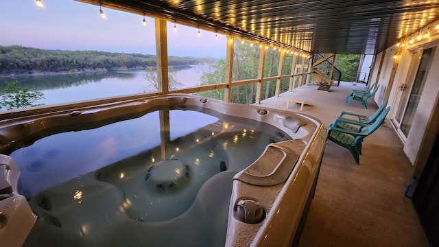 sunroom featuring a water view and a hot tub