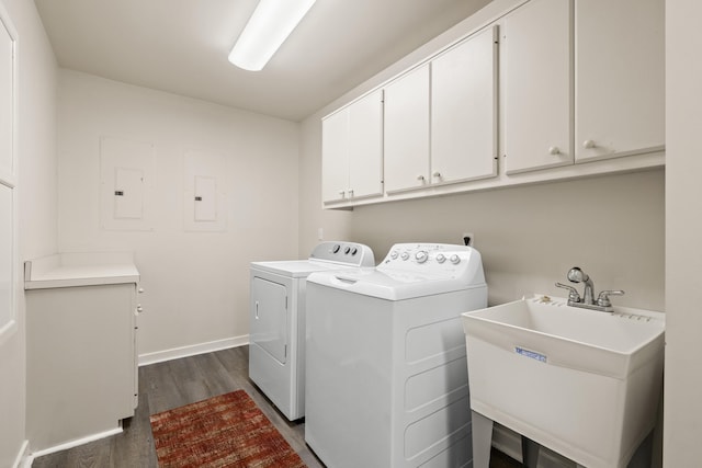 laundry area featuring cabinets, dark hardwood / wood-style flooring, sink, washing machine and clothes dryer, and electric panel