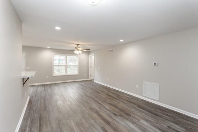 unfurnished living room featuring ceiling fan and dark hardwood / wood-style flooring