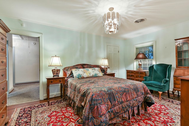 bedroom featuring hardwood / wood-style flooring, ornamental molding, and a chandelier