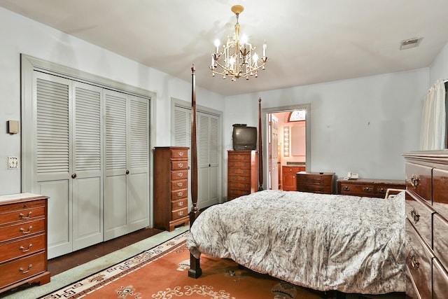 bedroom featuring an inviting chandelier, dark carpet, and two closets