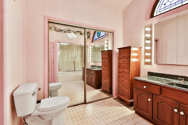 full bathroom with enclosed tub / shower combo, vanity, and toilet