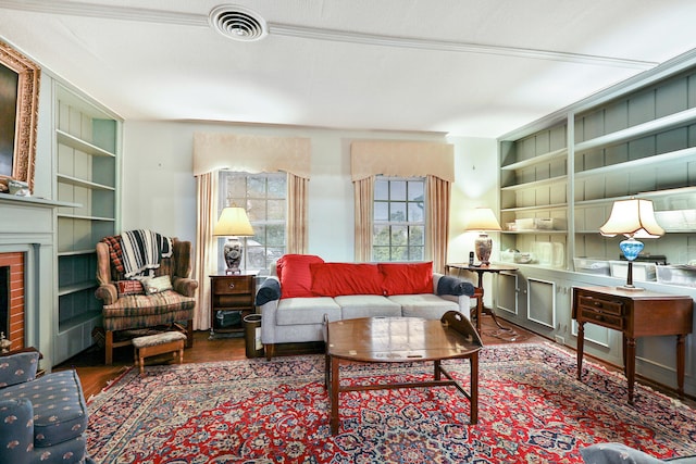 living room with dark hardwood / wood-style flooring, a brick fireplace, and built in shelves