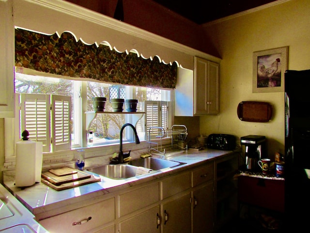 kitchen featuring sink, tile counters, and black fridge