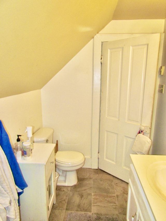 bathroom featuring vanity, lofted ceiling, and toilet