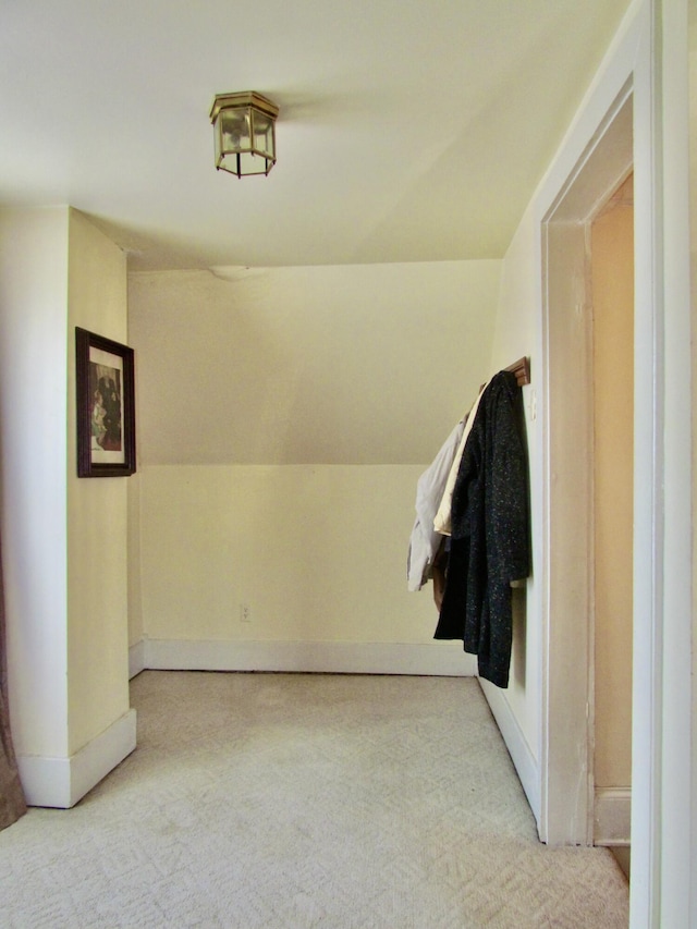 corridor featuring lofted ceiling and light colored carpet