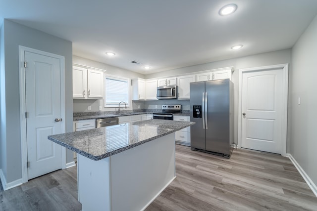 kitchen with a kitchen island, white cabinets, stone countertops, and appliances with stainless steel finishes