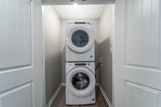 clothes washing area with stacked washer / drying machine and dark hardwood / wood-style floors