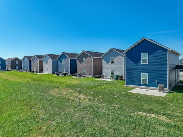 rear view of property with a yard, a patio, and central AC