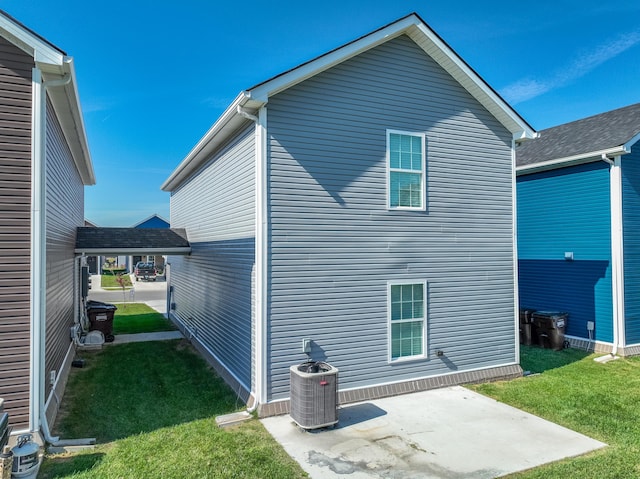 rear view of house featuring a yard, central AC unit, and a patio area