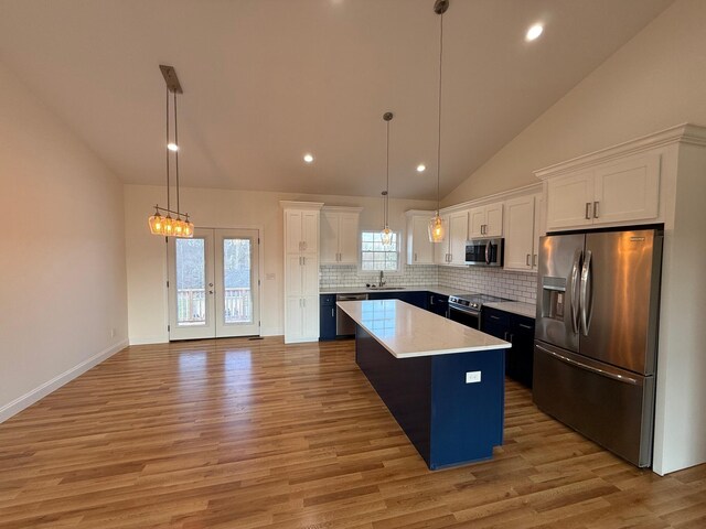 kitchen with stainless steel appliances, white cabinetry, a center island, and decorative light fixtures