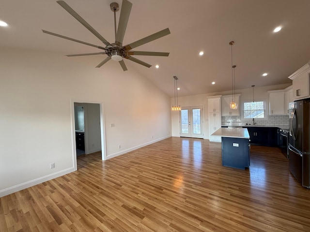 kitchen with pendant lighting, stainless steel refrigerator, white cabinetry, a center island, and light hardwood / wood-style floors