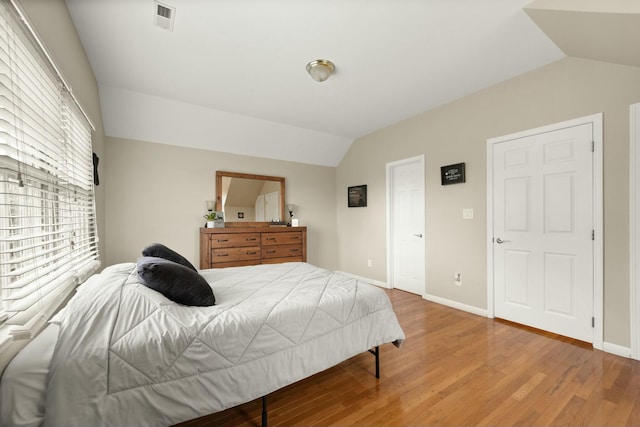 bedroom with multiple windows, hardwood / wood-style floors, and lofted ceiling