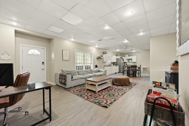 living room with light hardwood / wood-style floors and a drop ceiling