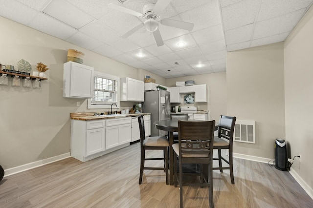 dining room featuring ceiling fan, a drop ceiling, and light wood-type flooring