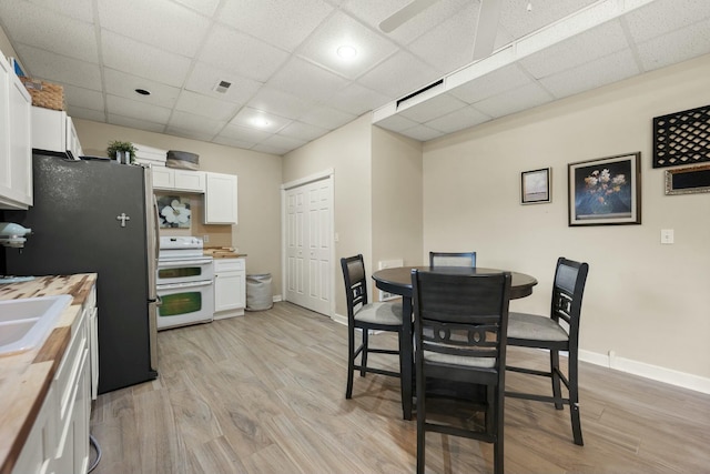 dining area with light hardwood / wood-style flooring and a drop ceiling