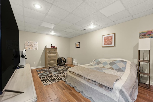 bedroom with a paneled ceiling and hardwood / wood-style flooring