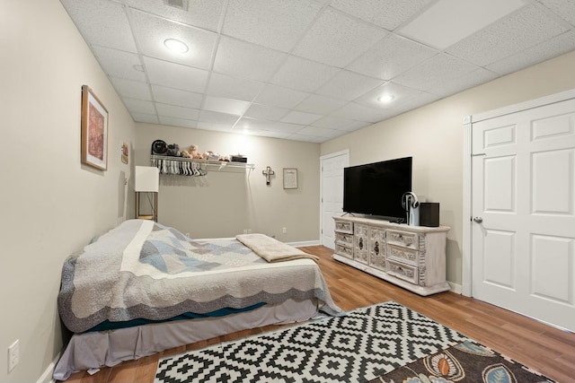 bedroom with wood-type flooring and a paneled ceiling