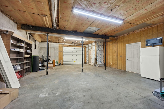 garage featuring wood walls and white fridge