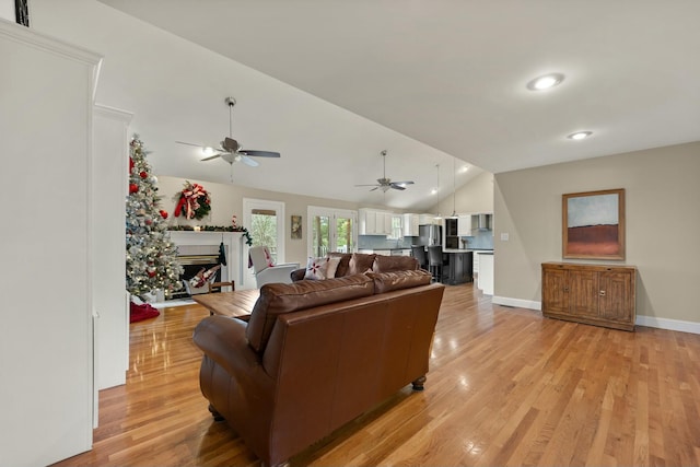 living room featuring lofted ceiling, ceiling fan, and light wood-type flooring