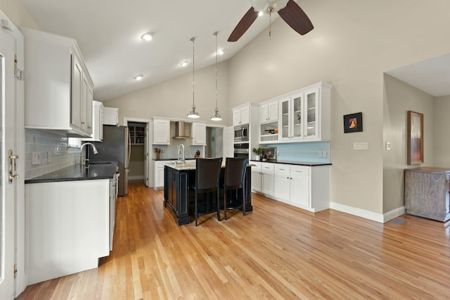 kitchen with hanging light fixtures, decorative backsplash, white cabinetry, and a kitchen island with sink