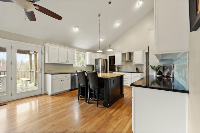 kitchen with backsplash, a center island with sink, wall chimney exhaust hood, white cabinetry, and stainless steel appliances