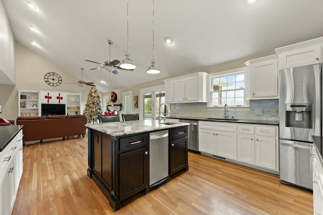 kitchen with hanging light fixtures, an island with sink, tasteful backsplash, white cabinetry, and stainless steel appliances