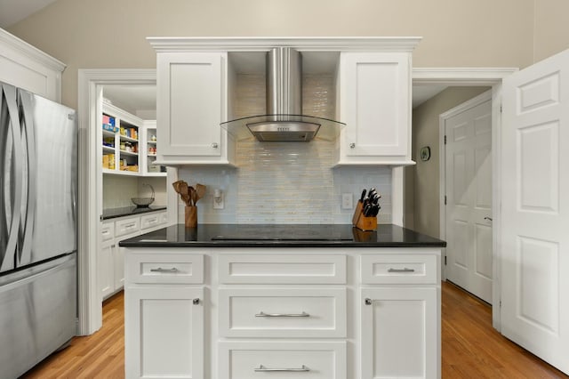 kitchen with white cabinets, black electric stovetop, stainless steel refrigerator, and wall chimney exhaust hood