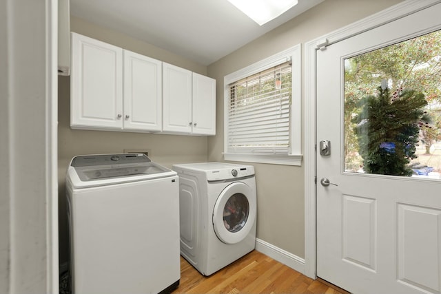 clothes washing area featuring washing machine and dryer, cabinets, and light hardwood / wood-style floors