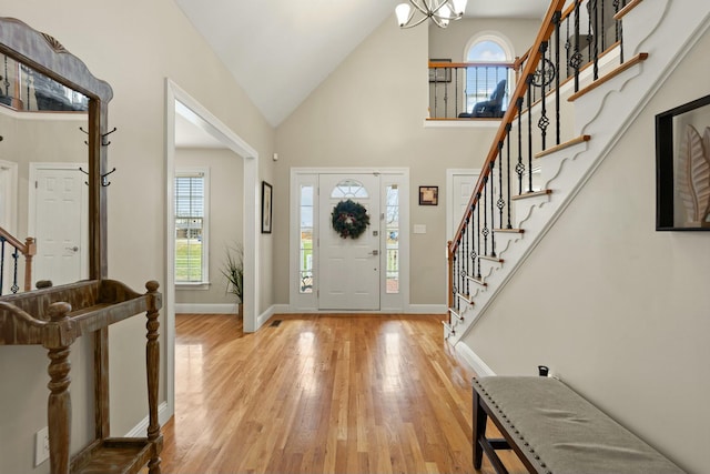 entrance foyer featuring an inviting chandelier, high vaulted ceiling, and light wood-type flooring