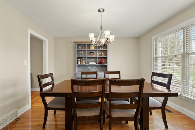 dining room with wood-type flooring and an inviting chandelier