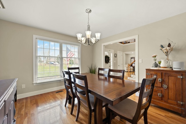 dining area with light hardwood / wood-style flooring and a notable chandelier