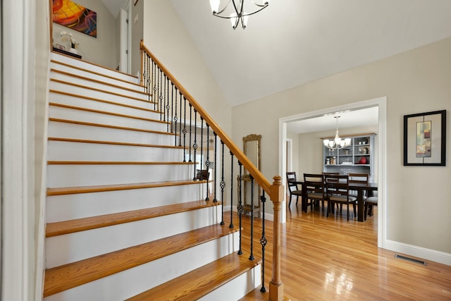 stairway featuring hardwood / wood-style flooring and an inviting chandelier