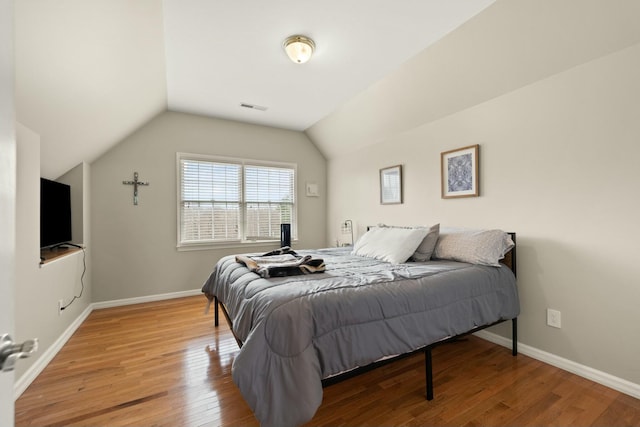 bedroom with wood-type flooring and vaulted ceiling